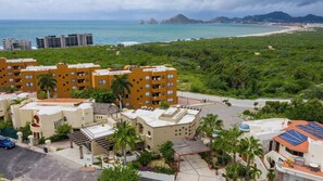 A residential area with multi-story buildings, a parking lot, and a view of the ocean. - Marbella lane - Chic Casa with Amazing OceanViews (Cabo San Lucas)