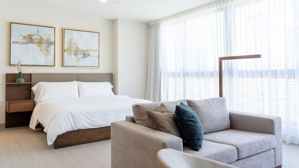 Ein Hotelzimmer mit einem Bett, einer Couch und zwei abstrakten Bildern an der Wand.