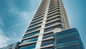 Ein Hochhaus mit modernem Design, gekennzeichnet durch eine markante vertikale Linie und spiegelnde Glasfenster.