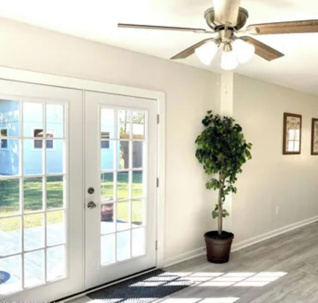 A hallway with a ceiling fan, a potted plant, and a door leading to an outdoor area.