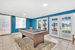 A pool table in a room with blue walls, white doors, and a view of a lake. - 3-bedroom Lake house in Pembroke Pines/Miami (Pembroke Pines)