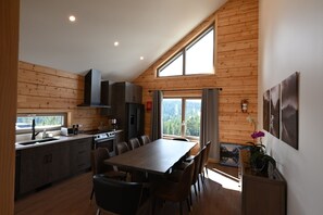 Eine moderne Küche mit Essbereich, Holzwänden und großen Fenstern.