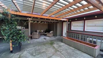 An outdoor patio with a wooden pergola, wicker furniture, and a built-in planter.