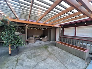 An outdoor patio with a wooden pergola, wicker furniture, and a built-in planter.