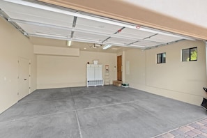 A garage with a concrete floor, a white storage unit, and a door leading to a room. - House of The Rising Sun - Hot Tub, Views, Forest (Sedona)