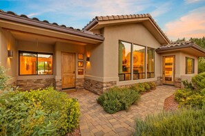 A modern house with a stone facade, large windows, and a well-maintained garden. - House of The Rising Sun - Hot Tub, Views, Forest (Sedona)