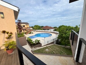 Ein Wohnhaus mit Schwimmbad, einer überdachten Terrasse und Blick auf benachbarte Häuser.