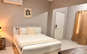Ein Schlafzimmer mit Bett, Nachttisch, Lampe und einer Tür.