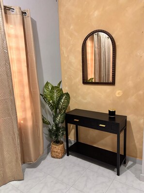 Un bagno con un mobile lavabo nero, uno specchio, una pianta in vaso e una tenda da doccia.