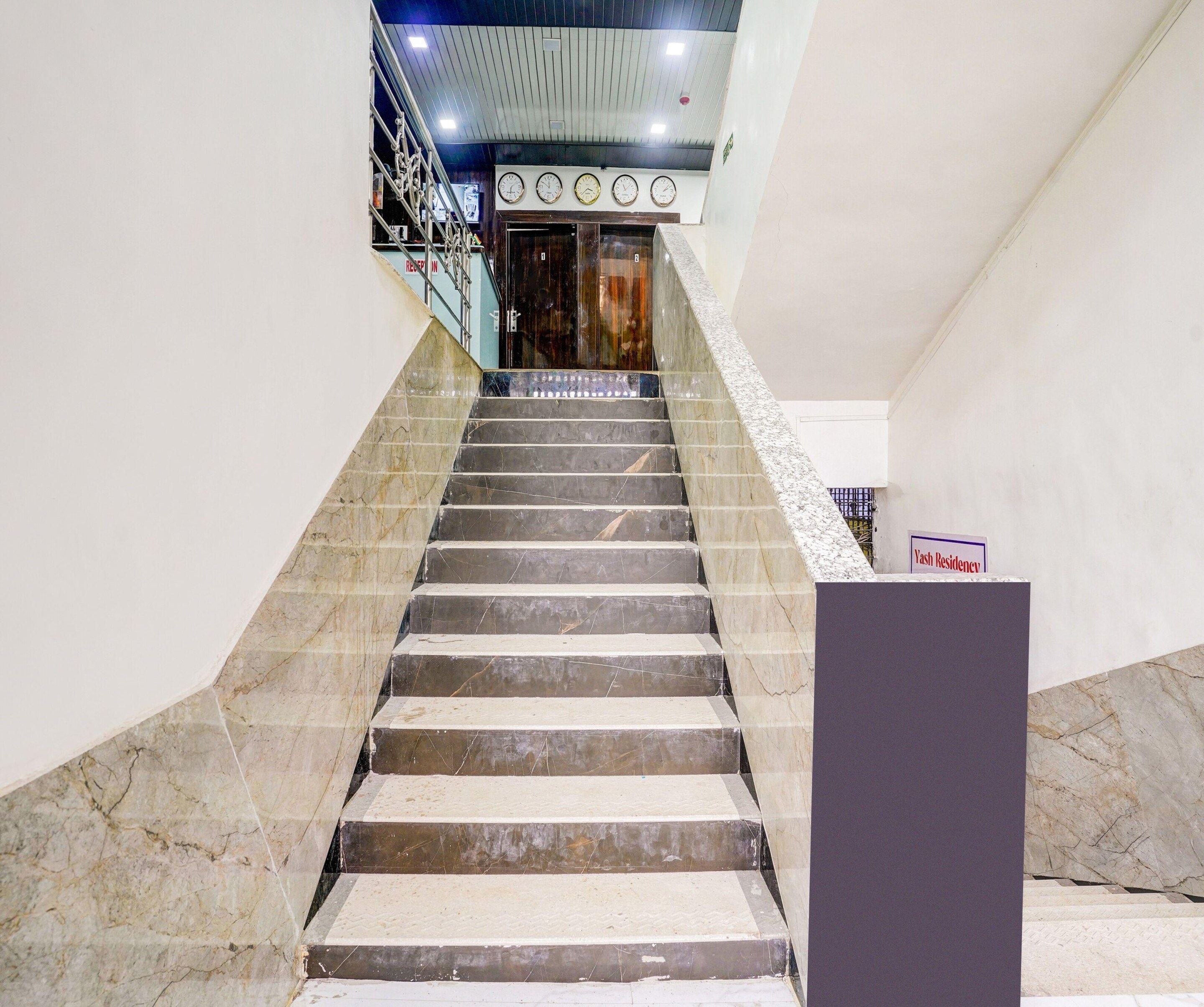 A staircase leading to a reception area with a sign indicating 'Yash Residency.'