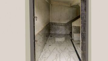 A hallway with a marble floor leading to a staircase.