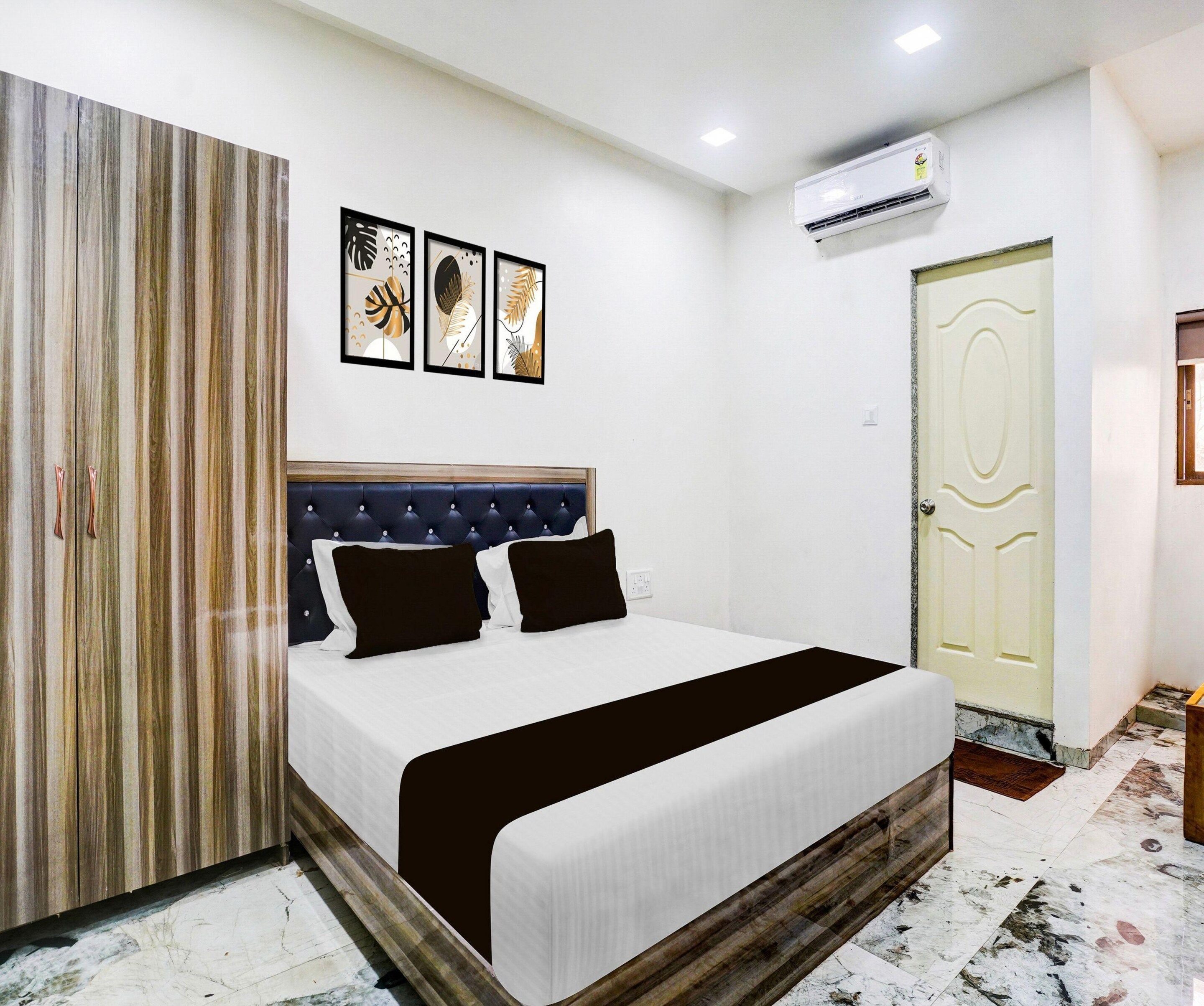 A bedroom with a bed, a wardrobe, a door, and three wall-mounted artworks.