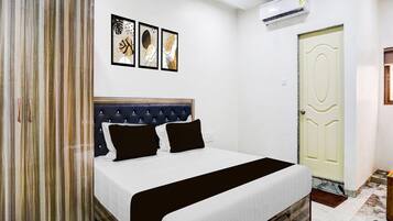 A bedroom with a bed, a wardrobe, a door, and three wall-mounted artworks.
