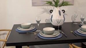 Une table à manger dressée avec des assiettes, des bols, des verres et des couverts.