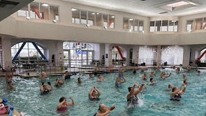 Piscina interna com várias pistas de natação e plataforma de mergulho.