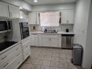 A kitchen with white cabinets, a stainless steel dishwasher, and a microwave.