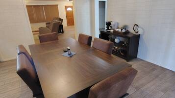Un comedor con mesa de madera y sillas de cuero, una estación de café y un mueble bajo con objetos decorativos.