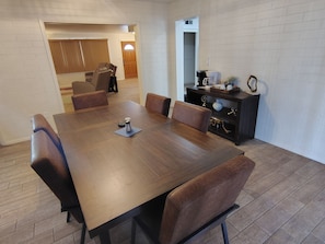 A dining area with a wooden table and leather chairs, a coffee station, and a small cabinet with decorative items. - Sunshine Sanctuary - Peace, Quiet & Sunshine - 55+ Active Senior Community (Sun City)