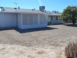 A house with a covered porch, a gravel driveway, and a tree.