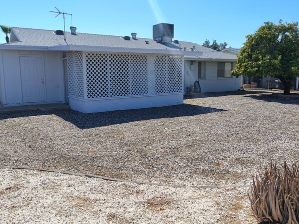 A house with a covered porch, a gravel driveway, and a tree.
