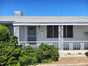 A house with a white exterior, a front porch with decorative railings, a mailbox, and a number sign.