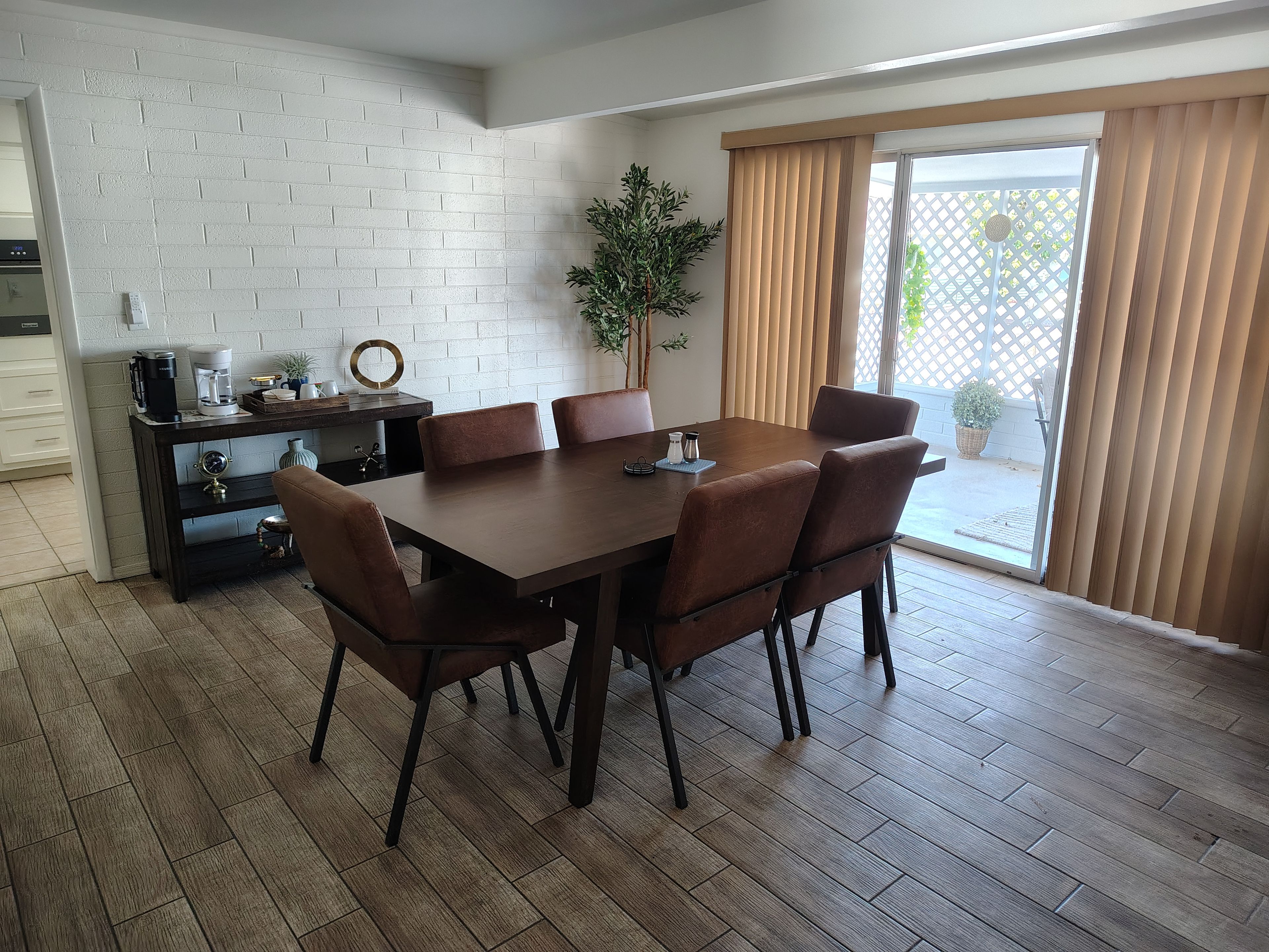 Un coin repas avec une table et des chaises en bois, une machine à café et une plante en pot.