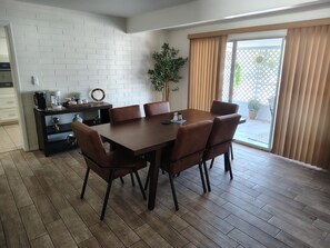 A dining area with a wooden table and chairs, a coffee machine, and a potted plant.