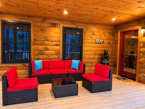 Ein rustikales Blockhaus-Interieur mit einem roten Sofagarnitur, einem Couchtisch und einer Bärenstatue.