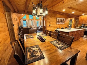 Ein Holzinterieur mit Esstisch, Stühlen, einer Couch und einer Küchenzeile.