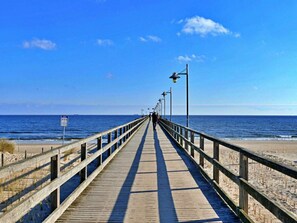 Un muelle de madera que conduce a la playa bajo un cielo despejado.