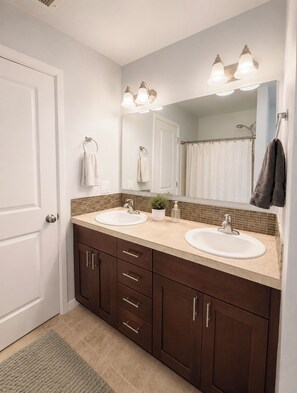 A bathroom with two sinks, a mirror, and a shower curtain. - Peaceful 3-bedroom house in charming Yelm perfect for relaxing getaway (Yelm)