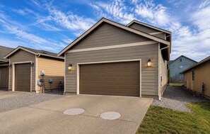 A residential building with a garage, a driveway, and a grassy area. - Peaceful 3-bedroom house in charming Yelm perfect for relaxing getaway (Yelm)