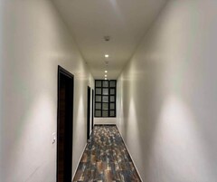 Um corredor com piso estampado, paredes brancas e uma porta à esquerda.