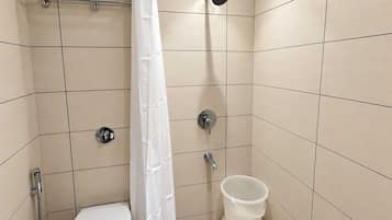 A small, tiled bathroom with a toilet, a shower, and a toilet paper holder.