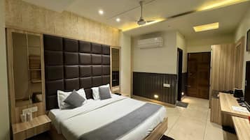 A modern bedroom with a large bed, built-in wardrobe, and a desk area.