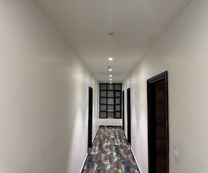 A hallway with a patterned floor, white walls, and a door at the end.