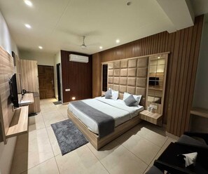 A modern bedroom with a large bed, bedside tables, a TV, and a wardrobe.