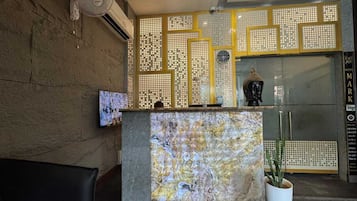 A reception area with a marble counter, a potted plant, and a decorative wall with a geometric pattern.