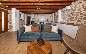 A living room with a blue sofa, a round wooden coffee table, and a wicker chair. - Cozy home in Stankovci with private swimming pool, can be inside or outside (Stankovci)