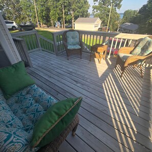 A wooden deck with outdoor furniture, including a sofa and chairs, and a boat in the background. - Kentucky Lake Vista (Gilbertsville)