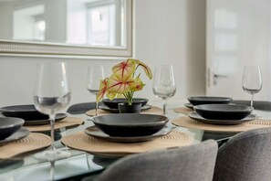 A dining table set with black plates, clear wine glasses, and a potted plant with striped leaves. - 2-bed Flat Near Regent's Park - Patio - Sleeps 6 (London)