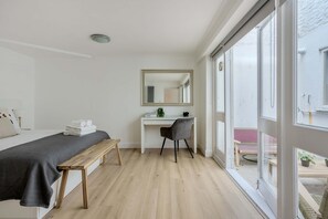 A bedroom with a bed, a desk, a chair, and a large window. - 2-bed Flat Near Regent's Park - Patio - Sleeps 6 (London)
