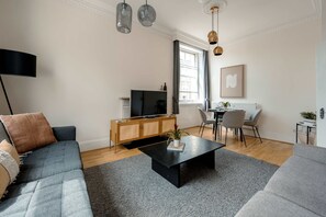 Un salon moderne avec un canapé, une table basse et un téléviseur.