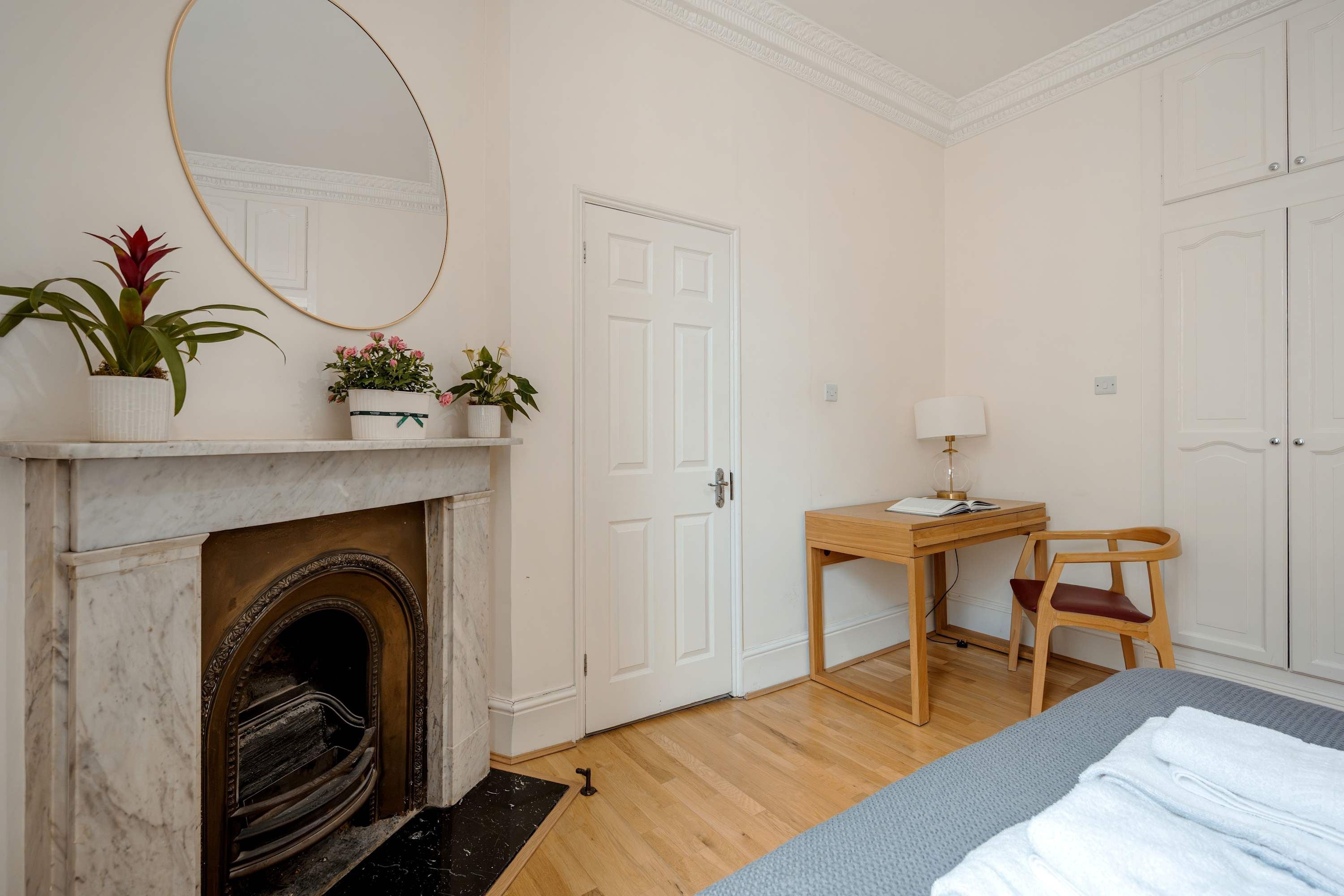 Une chambre avec une cheminée, un bureau avec une chaise et un lit.