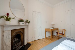 Une chambre avec une cheminée, un bureau avec une chaise et un lit.