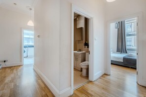 Eine moderne Wohnung mit Holzboden, einem Badezimmer mit Toilette und Waschbecken sowie einem Bett mit Fenster.