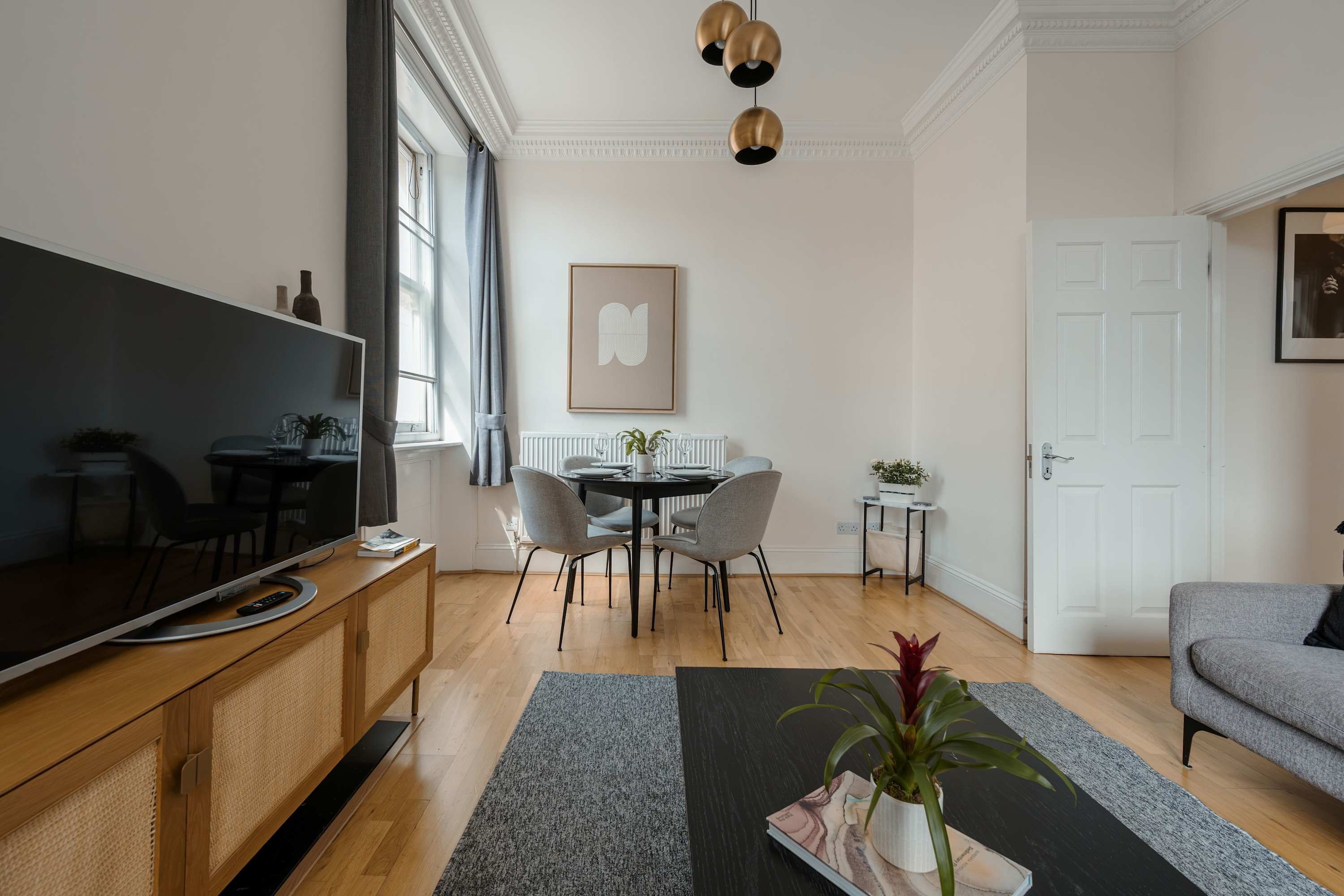 Un salon moderne avec un téléviseur à écran plat, une table à manger, des chaises et un canapé.