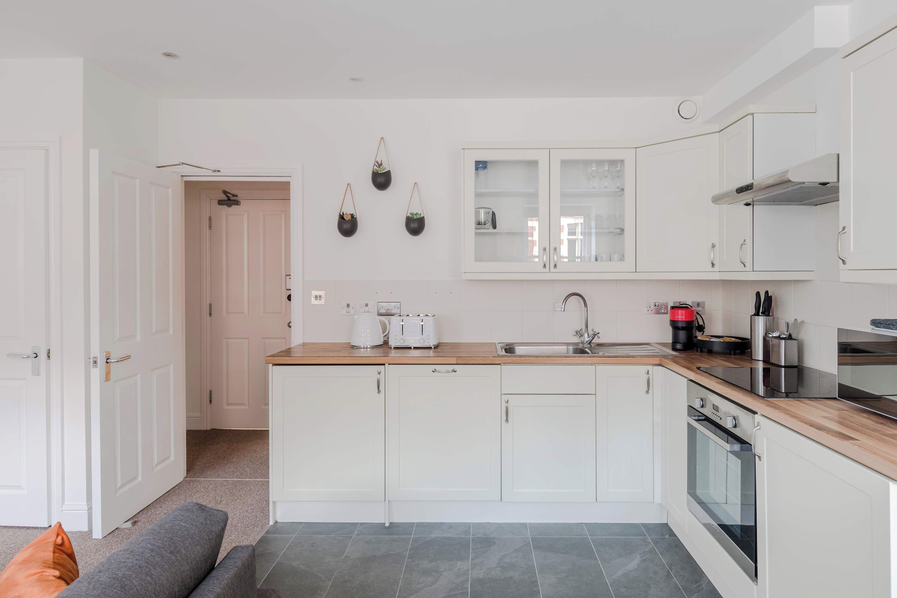 A modern kitchen with white cabinets, a wooden countertop, a built-in oven, and a sink.