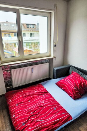 A small room with a bed, a window, and a radiator. - Einfache 1-Zimmer Wohnung by Interhome (Bad Wörishofen)