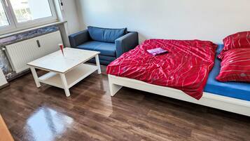 Ein Zimmer mit einem Bett, einer Couch, einem kleinen Tisch und einer Heizung.